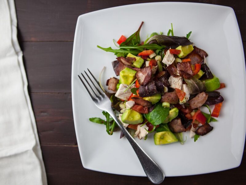 Salad with grilled meat and avocado on a square plate