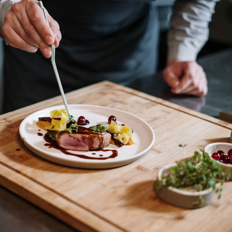 A chef finishing a plated dish in the kitchen
